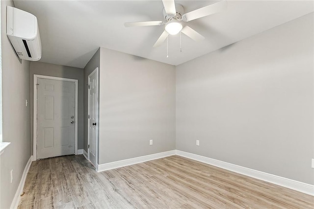 empty room featuring a wall mounted AC, ceiling fan, and light hardwood / wood-style floors