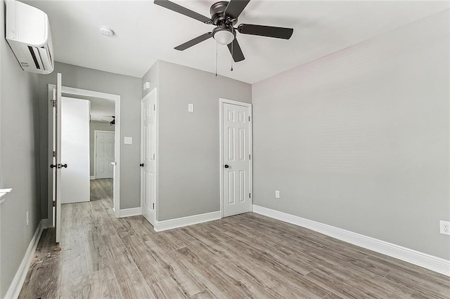 unfurnished bedroom featuring ceiling fan, light hardwood / wood-style floors, and a wall mounted AC