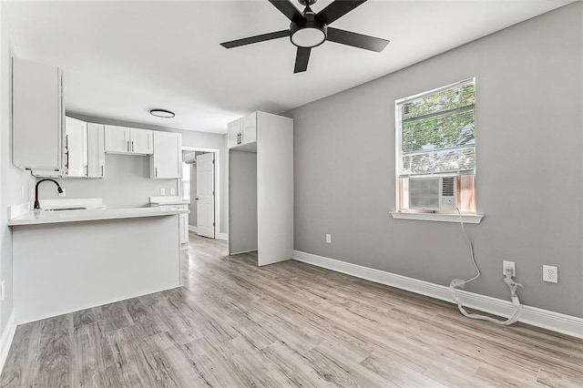 kitchen with kitchen peninsula, light wood-type flooring, white cabinetry, and ceiling fan