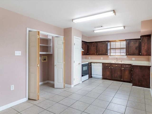 kitchen featuring dark brown cabinetry, white appliances, sink, and light tile patterned floors