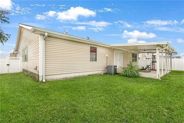 rear view of property with a patio area, a yard, and central AC