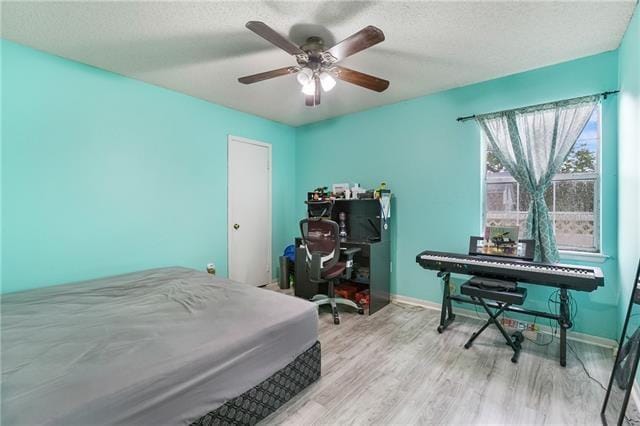 bedroom with ceiling fan, a textured ceiling, and light hardwood / wood-style flooring