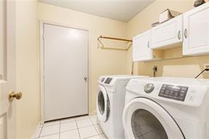 clothes washing area with light tile patterned flooring, cabinets, and washing machine and clothes dryer