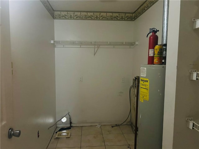 laundry area featuring light tile patterned floors and water heater