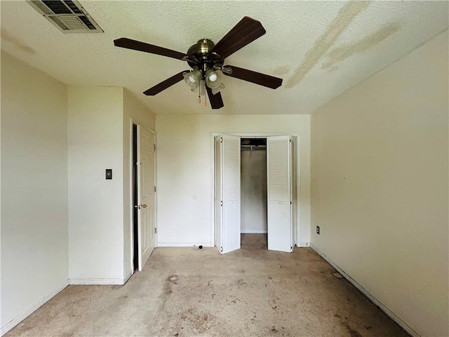 unfurnished bedroom featuring ceiling fan, a closet, light colored carpet, and a textured ceiling