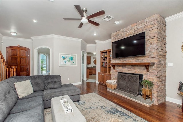 living room with a fireplace, dark wood-type flooring, ceiling fan, and ornamental molding