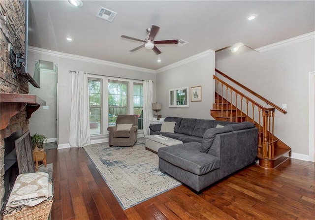 living room with a stone fireplace, crown molding, ceiling fan, and dark hardwood / wood-style floors