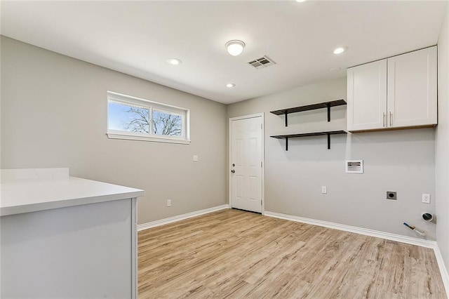 laundry area featuring gas dryer hookup, cabinets, light hardwood / wood-style flooring, electric dryer hookup, and washer hookup