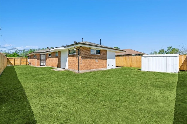 back of house with a storage shed and a lawn