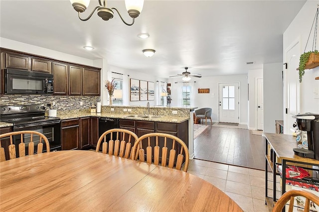 kitchen with light stone countertops, dark brown cabinetry, sink, black appliances, and light hardwood / wood-style floors