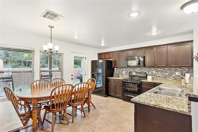 kitchen with sink, hanging light fixtures, light stone counters, a chandelier, and black appliances