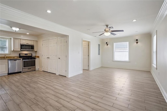 kitchen with a healthy amount of sunlight, ornamental molding, stainless steel appliances, and light wood-type flooring