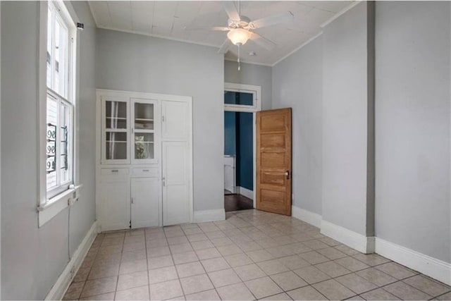 tiled empty room featuring ceiling fan and ornamental molding