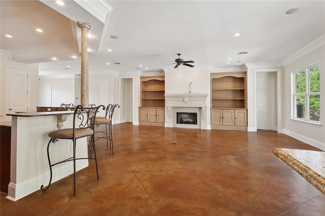 living room featuring crown molding, ceiling fan, built in shelves, ornate columns, and a fireplace