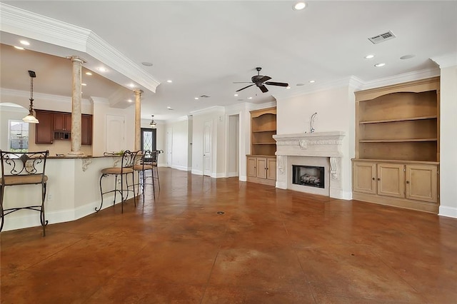 unfurnished living room featuring built in shelves, ornate columns, ceiling fan, and crown molding