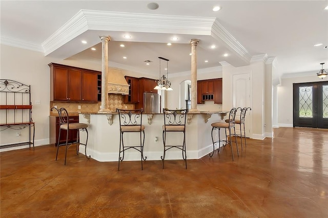 kitchen featuring pendant lighting, backsplash, a kitchen breakfast bar, crown molding, and stainless steel fridge