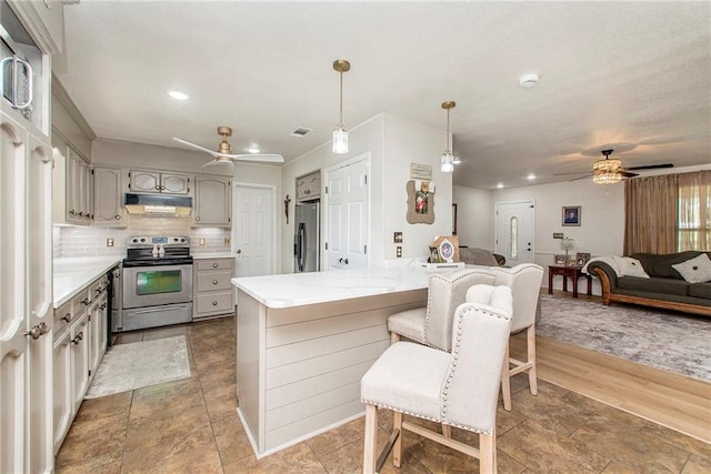 kitchen with gray cabinetry, backsplash, hardwood / wood-style floors, decorative light fixtures, and appliances with stainless steel finishes