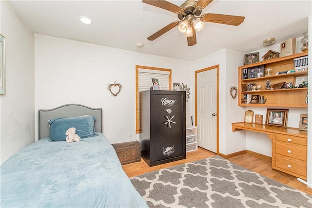 bedroom featuring light wood-type flooring, built in desk, and ceiling fan