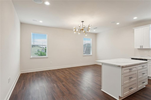 kitchen featuring dark wood-type flooring, white cabinetry, light stone counters, a center island, and pendant lighting