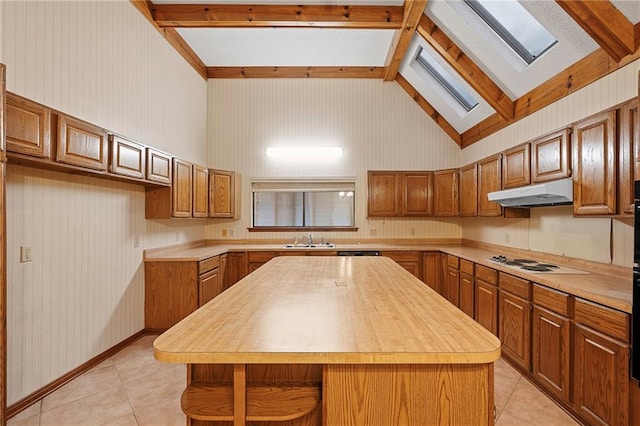 1391 E Ashton Ct, Slidell, LA 70460 - kitchen with a skylight, under cabinet range hood, light tile patterned floors, a sink, and brown cabinetry