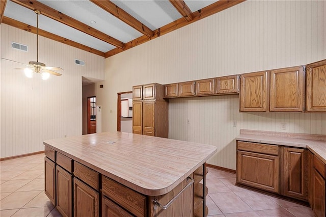 1391 E Ashton Ct, Slidell, LA 70460 - kitchen with light tile patterned flooring, brown cabinetry, beam ceiling, light countertops, and ceiling fan