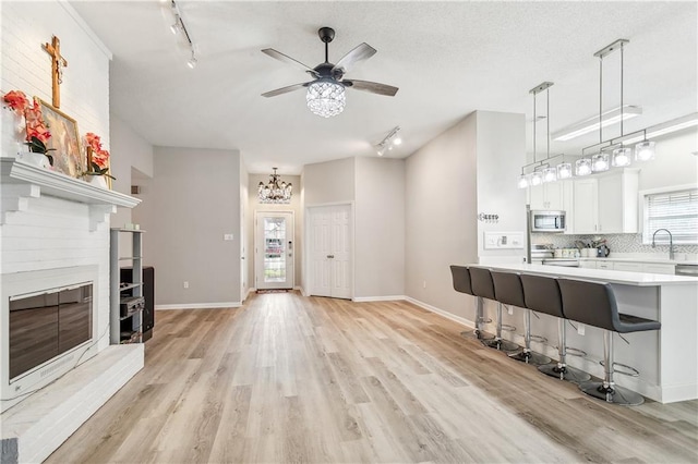 living room featuring ceiling fan with notable chandelier, light hardwood / wood-style flooring, and track lighting