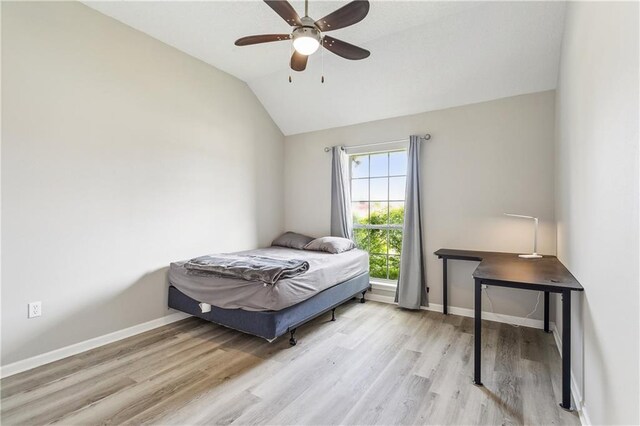 bedroom with ceiling fan, light wood-type flooring, and vaulted ceiling