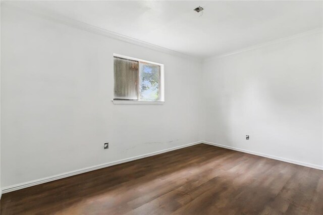 empty room featuring ornamental molding and dark wood-type flooring