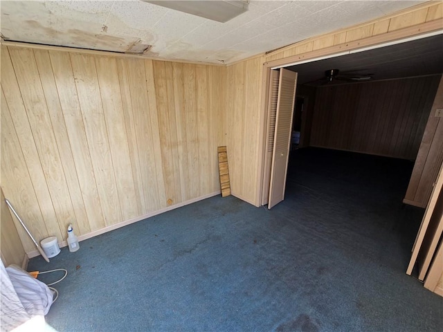 spare room with dark colored carpet and wood walls