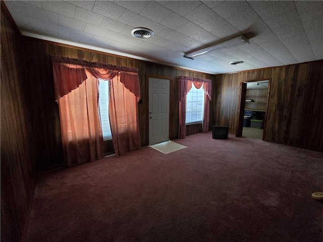 carpeted empty room with wood walls