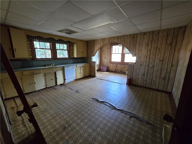 kitchen featuring a paneled ceiling, wood walls, plenty of natural light, and white dishwasher