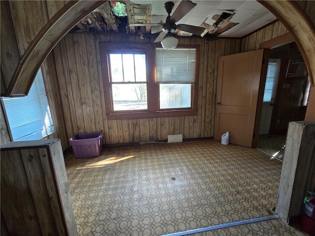 bonus room with ceiling fan and wooden walls