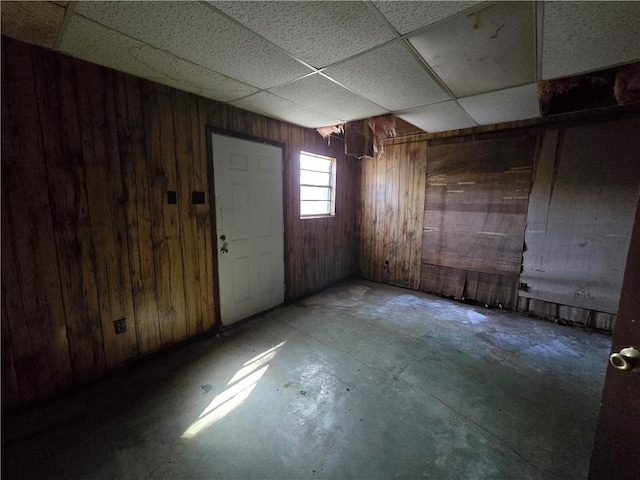 basement with wood walls and a drop ceiling