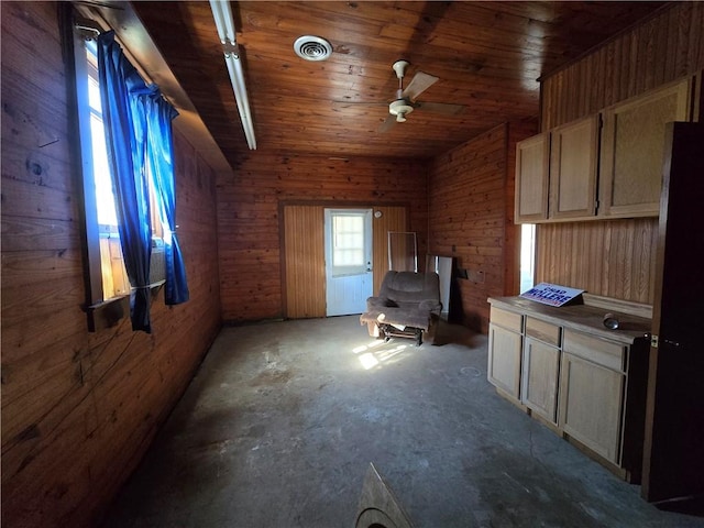 interior space featuring light brown cabinetry, concrete flooring, ceiling fan, wooden ceiling, and wood walls