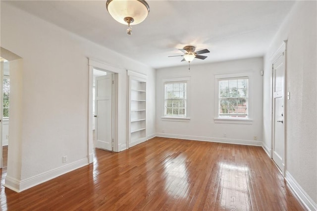 unfurnished room featuring hardwood / wood-style floors, ceiling fan, and built in features