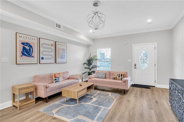 living room featuring an inviting chandelier, light hardwood / wood-style flooring, and crown molding