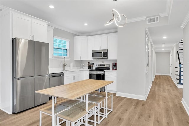 kitchen with stainless steel appliances, sink, pendant lighting, light hardwood / wood-style floors, and white cabinetry