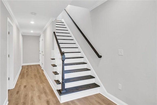 staircase with wood-type flooring and crown molding