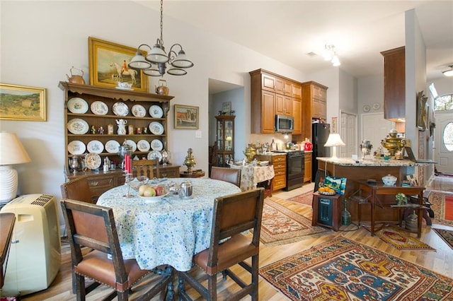 dining area with light hardwood / wood-style floors and an inviting chandelier