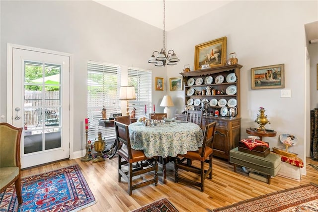 dining area with light hardwood / wood-style flooring, a towering ceiling, and a chandelier