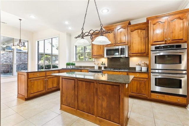 kitchen with decorative light fixtures, light tile patterned flooring, stainless steel appliances, and a kitchen island