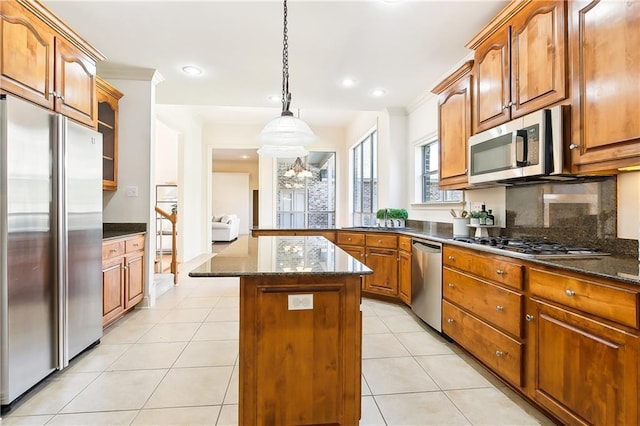 kitchen featuring light tile patterned floors, stainless steel appliances, decorative backsplash, a kitchen island, and decorative light fixtures