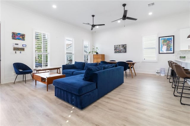 living room with light hardwood / wood-style flooring, ceiling fan, and ornamental molding