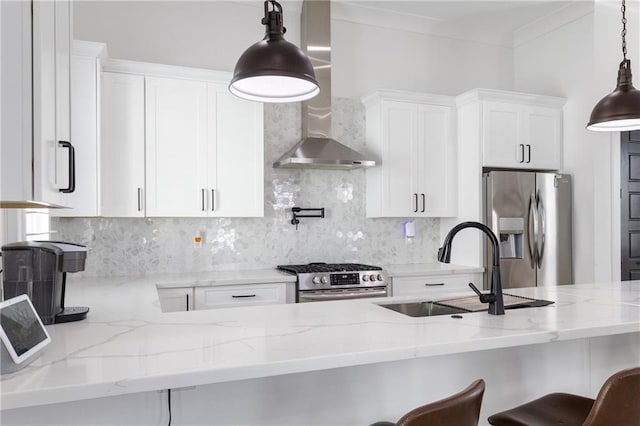 kitchen featuring wall chimney exhaust hood, light stone counters, white cabinets, and appliances with stainless steel finishes