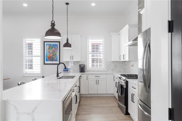 kitchen with appliances with stainless steel finishes, light stone counters, sink, pendant lighting, and white cabinets