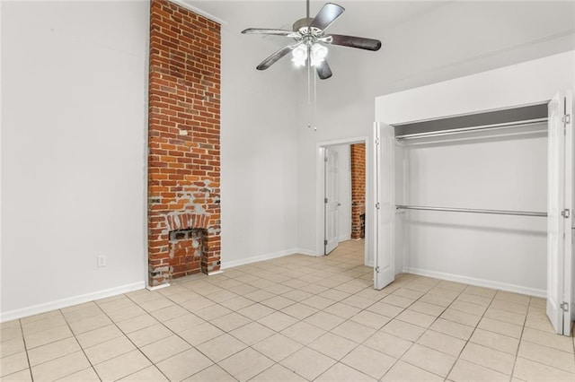 unfurnished bedroom featuring a fireplace, light tile patterned floors, a closet, and ceiling fan