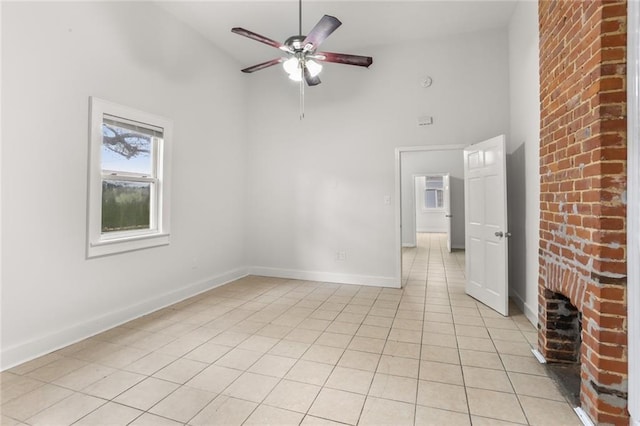 tiled empty room featuring ceiling fan, a fireplace, and high vaulted ceiling