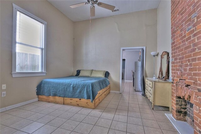 tiled bedroom featuring a brick fireplace and ceiling fan