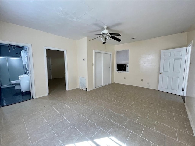 interior space with cooling unit, ensuite bathroom, ceiling fan, and light tile patterned floors