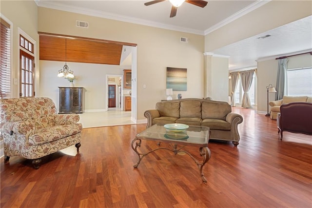 living room featuring hardwood / wood-style floors, ceiling fan with notable chandelier, and ornamental molding